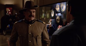 Movie still from “Night at the Museum” (2006), directed by Shawn Levy – A man in a military uniform wearing a hat and eye glasses; Medium shot, Over the shoulder angle