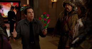 Movie still from “Night at the Museum” (2006), directed by Shawn Levy – A man holding a bouquet of flowers in front of another man; Medium shot, Over the shoulder angle