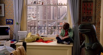Movie still from “Night at the Museum” (2006), directed by Shawn Levy – A person sitting on a window sill looking at a book; Wide shot, High angle