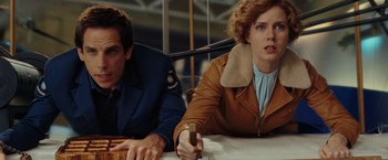 Movie still from “Night at the Museum: Battle of the Smithsonian” (2009), directed by Shawn Levy – A man and a woman sitting next to each other on a table; Medium shot, Low angle