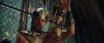 Movie still from “Night at the Museum: Battle of the Smithsonian” (2009), directed by Shawn Levy – A man in a costume holding an hourglass in his hands; Medium shot, Low angle