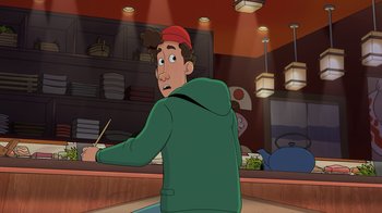 Movie still from “Night at the Museum: Kahmunrah Rises Again” (2022), directed by Justin Lovell – A man in a green jacket is sitting at a table; Medium shot, Over the shoulder angle