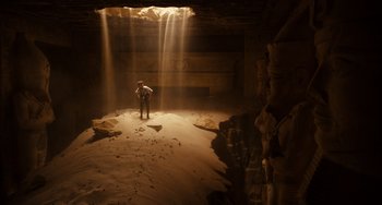 Movie still from “Night at the Museum: Secret of the Tomb” (2014), directed by Shawn Levy – A man standing in a cave with light coming out of the cave; Extreme Wide shot, High angle