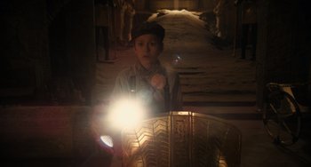 Movie still from “Night at the Museum: Secret of the Tomb” (2014), directed by Shawn Levy – A young man holding a flashlight in front of a tire; Medium shot, High angle