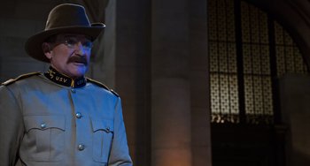 Movie still from “Night at the Museum: Secret of the Tomb” (2014), directed by Shawn Levy – A man in a blue uniform and a black hat standing in front of a building; Medium shot, Over the shoulder angle
