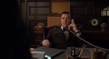 Movie still from “Night at the Museum: Secret of the Tomb” (2014), directed by Shawn Levy – A man sitting at a desk talking on a phone; Medium shot, Over the shoulder angle