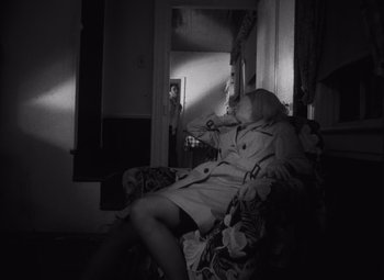 Movie still from “Night of the Living Dead” (1968), directed by George A. Romero – A woman sitting on a chair in a room; Wide shot, High angle