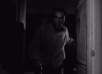 Movie still from “Night of the Living Dead” (1968), directed by George A. Romero – A black and white photo of a man walking in a hallway; Medium shot, High angle