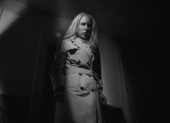 Movie still from “Night of the Living Dead” (1968), directed by George A. Romero – A woman wearing a trench coat standing in a room; Medium shot, Low angle