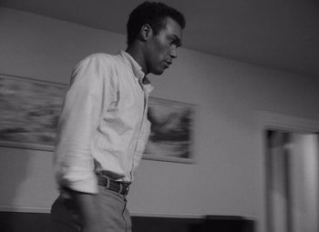 Movie still from “Night of the Living Dead” (1968), directed by George A. Romero – A black and white photo of a man standing in a living room; Medium shot, Low angle