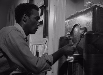 Movie still from “Night of the Living Dead” (1968), directed by George A. Romero – A black and white photo of a man putting something in a machine; Medium shot, Low angle