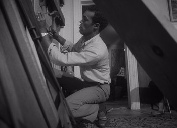 Movie still from “Night of the Living Dead” (1968), directed by George A. Romero – A black and white photo of a man working on an easel; Medium shot, Low angle