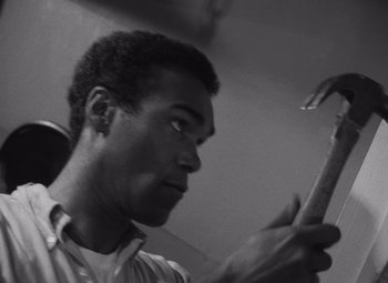 Movie still from “Night of the Living Dead” (1968), directed by George A. Romero – A black and white photo of a man looking at his cell phone; Close Up shot, Low angle