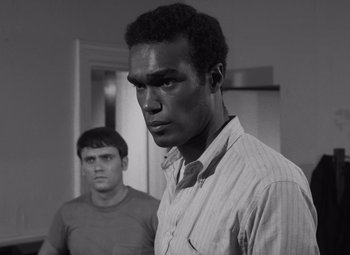 Movie still from “Night of the Living Dead” (1968), directed by George A. Romero – A man standing next to another man in front of a door; Close Up shot, Over the shoulder angle