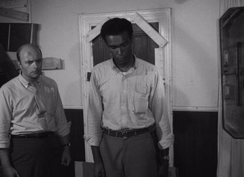 Movie still from “Night of the Living Dead” (1968), directed by George A. Romero – A man standing in front of a door in a room; Medium shot, Low angle