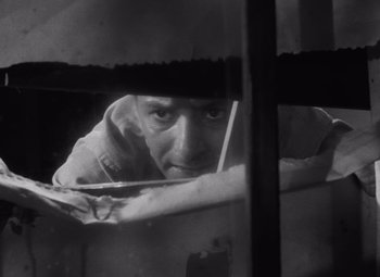 Movie still from “Night of the Living Dead” (1968), directed by George A. Romero – A black and white photo of a man looking out a window; Close Up shot, Low angle