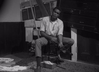 Movie still from “Night of the Living Dead” (1968), directed by George A. Romero – Black and white photograph of a man sitting on a chair; Medium shot, High angle