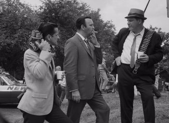 Movie still from “Night of the Living Dead” (1968), directed by George A. Romero – A group of men standing next to each other on a field; Medium shot, Low angle