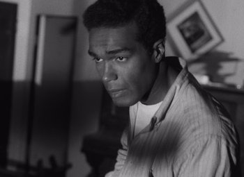 Movie still from “Night of the Living Dead” (1968), directed by George A. Romero – A black - and - white photo of a man looking at the camera; Close Up shot, High angle