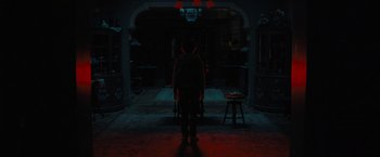 Movie still from “Nightbooks” (2021), directed by David Yarovesky – A person standing in a dark room at night; Wide shot, Overhead angle