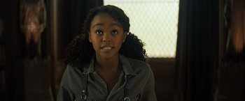 Movie still from “Nightbooks” (2021), directed by David Yarovesky – A young woman with a big curly black hair; Close Up shot, Over the shoulder angle
