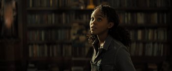 Movie still from “Nightbooks” (2021), directed by David Yarovesky – A young girl is standing in front of a book shelf; Close Up shot, Low angle