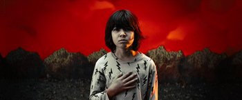 Movie still from “Nightbooks” (2021), directed by David Yarovesky – A young person with long black hair is holding his hand to his chest; Medium shot, Overhead angle