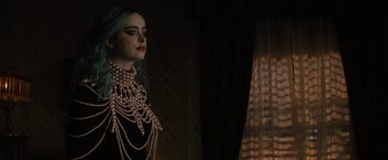 Movie still from “Nightbooks” (2021), directed by David Yarovesky – A woman with blue hair wearing a black dress and pearls; Close Up shot, Low angle