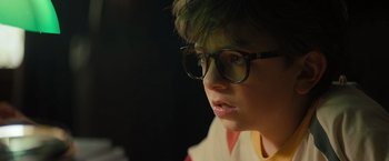 Movie still from “Nightbooks” (2021), directed by David Yarovesky – A young boy wearing glasses looking at the camera; Close Up shot, Over the shoulder angle