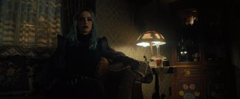 Movie still from “Nightbooks” (2021), directed by David Yarovesky – A woman with blue hair sitting in a chair next to a lamp; Medium shot, Low angle
