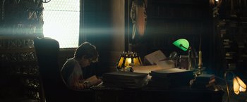 Movie still from “Nightbooks” (2021), directed by David Yarovesky – A young boy is reading a book in a library; Medium shot, Low angle