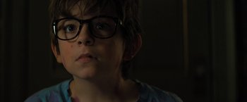 Movie still from “Nightbooks” (2021), directed by David Yarovesky – A young boy wearing glasses looking at the camera; Close Up shot, Over the shoulder angle