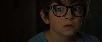 Movie still from “Nightbooks” (2021), directed by David Yarovesky – A young boy wearing glasses looking up at the sky; Close Up shot, High angle