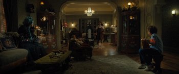 Movie still from “Nightbooks” (2021), directed by David Yarovesky – A man and a woman are sitting in a living room; Wide shot, High angle