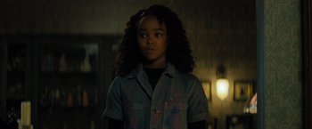 Movie still from “Nightbooks” (2021), directed by David Yarovesky – A young girl is standing in the dark; Close Up shot, Over the shoulder angle