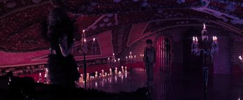 Movie still from “Nightbooks” (2021), directed by David Yarovesky – A man standing in front of candles in a room; Wide shot, High angle