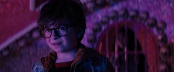 Movie still from “Nightbooks” (2021), directed by David Yarovesky – A young boy wearing glasses in a room with skulls on the walls; Close Up shot, Over the shoulder angle