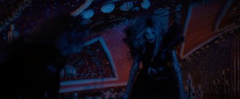 Movie still from “Nightbooks” (2021), directed by David Yarovesky – A woman in a black dress is standing in the dark; Medium shot, Overhead angle