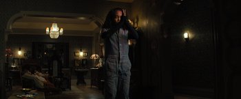 Movie still from “Nightbooks” (2021), directed by David Yarovesky – A person standing in a dark room holding their hands up to their face; Medium shot, Low angle