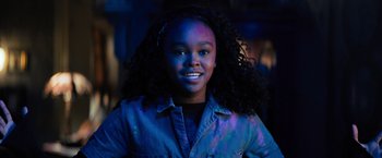 Movie still from “Nightbooks” (2021), directed by David Yarovesky – A young woman with a bright blue light shining on her face; Close Up shot, Over the shoulder angle