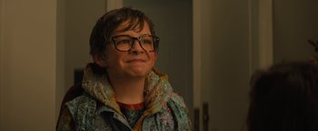 Movie still from “Nightbooks” (2021), directed by David Yarovesky – A young person wearing glasses and a jacket; Close Up shot, Over the shoulder angle