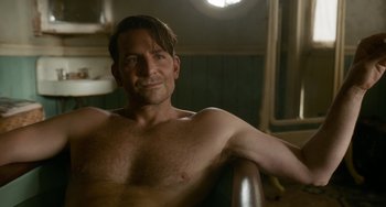Movie still from “Nightmare Alley” (2021), directed by Guillermo del Toro – A shirtless man sitting in a chair in a room; Close Up shot, Over the shoulder angle
