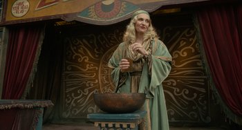 Movie still from “Nightmare Alley” (2021), directed by Guillermo del Toro – A woman dressed in medieval garb standing in front of a bowl; Medium shot, Low angle