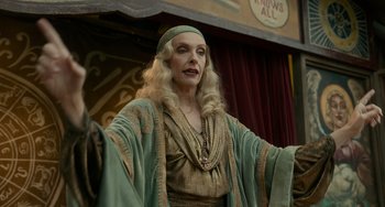 Movie still from “Nightmare Alley” (2021), directed by Guillermo del Toro – An old woman in a green and gold dress; Medium shot, Low angle