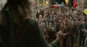 Movie still from “Nightmare Alley” (2021), directed by Guillermo del Toro – A crowd of people are gathered around a woman; Wide shot, High angle
