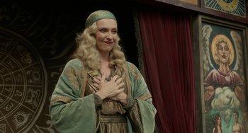 Movie still from “Nightmare Alley” (2021), directed by Guillermo del Toro – A woman dressed in medieval clothing and holding her hands to her chest; Medium shot, Over the shoulder angle