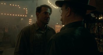 Movie still from “Nightmare Alley” (2021), directed by Guillermo del Toro – Two men standing next to each other on a city street; Medium shot, Over the shoulder angle