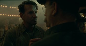 Movie still from “Nightmare Alley” (2021), directed by Guillermo del Toro – Two men talking to each other in a dimly - lit room; Close Up shot, Over the shoulder angle