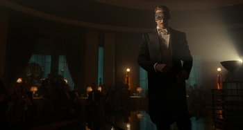 Movie still from “Nightmare Alley” (2021), directed by Guillermo del Toro – A man in a suit and a mask standing in a room; Wide shot, Low angle