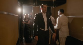 Movie still from “Nightmare Alley” (2021), directed by Guillermo del Toro – A man in a tuxedo walking down a hall way; Wide shot, Over the shoulder angle